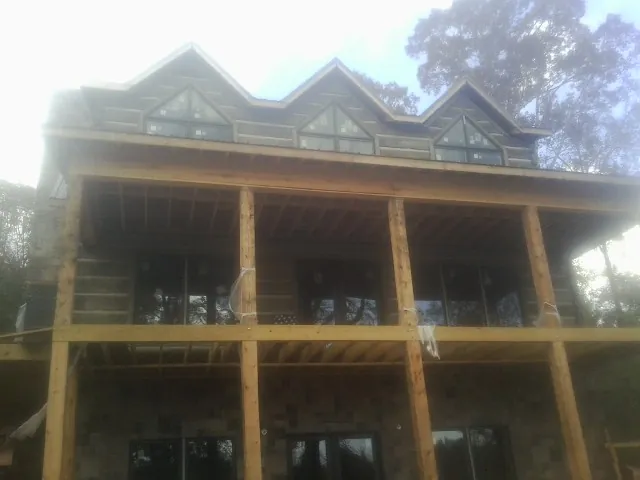 Dormers and porch framing on a large log home under construction — Roof Coating work by our crew in Hadley